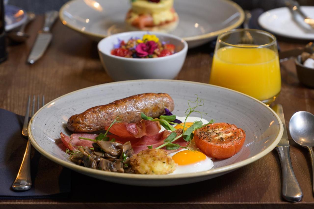 a plate of breakfast food with sausage and eggs on a table at Eight in Bath